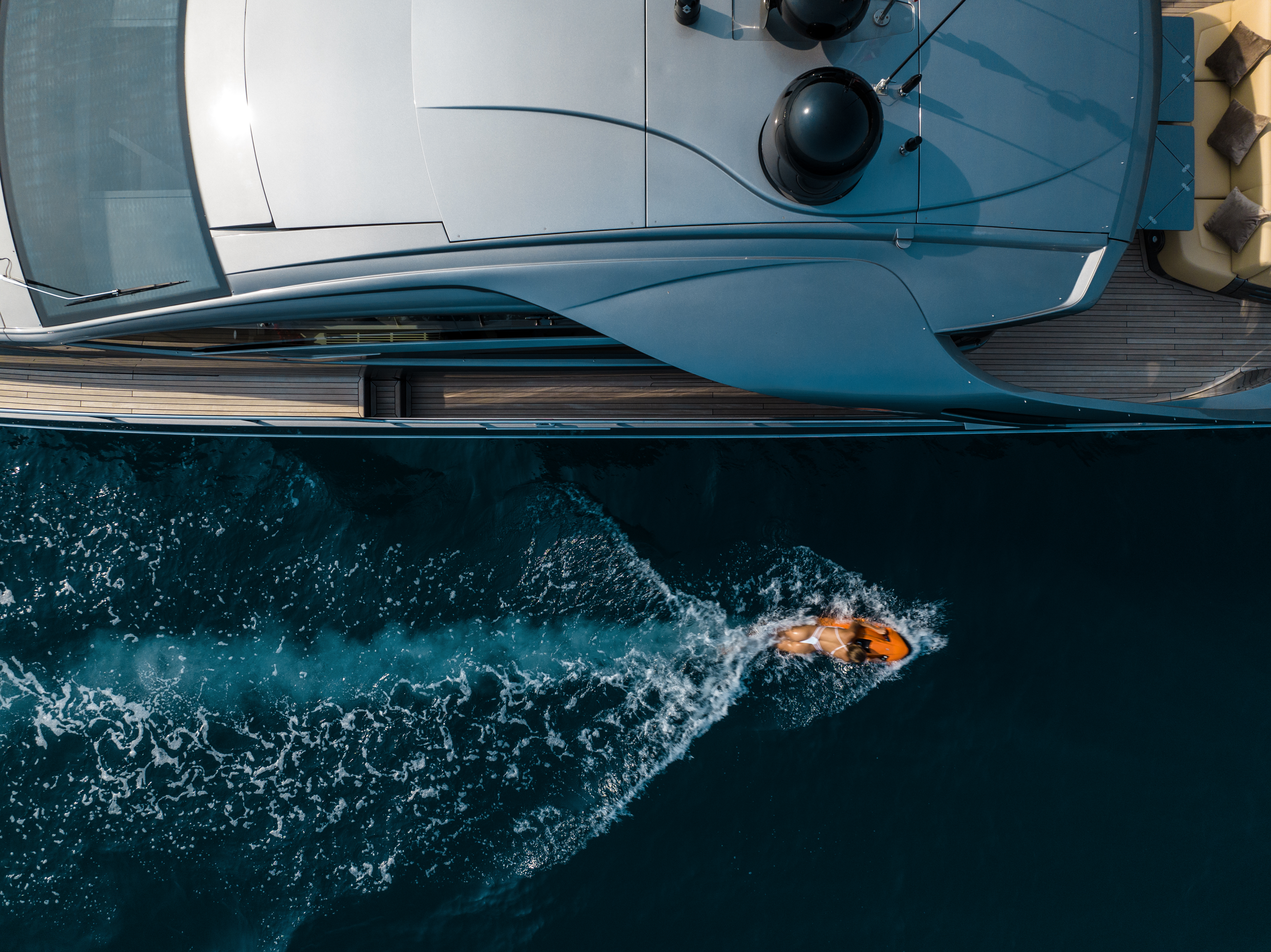 Aerial view of luxury superyacht at anchor with swimmer entering the Mediterranean — private yacht charter lifestyle