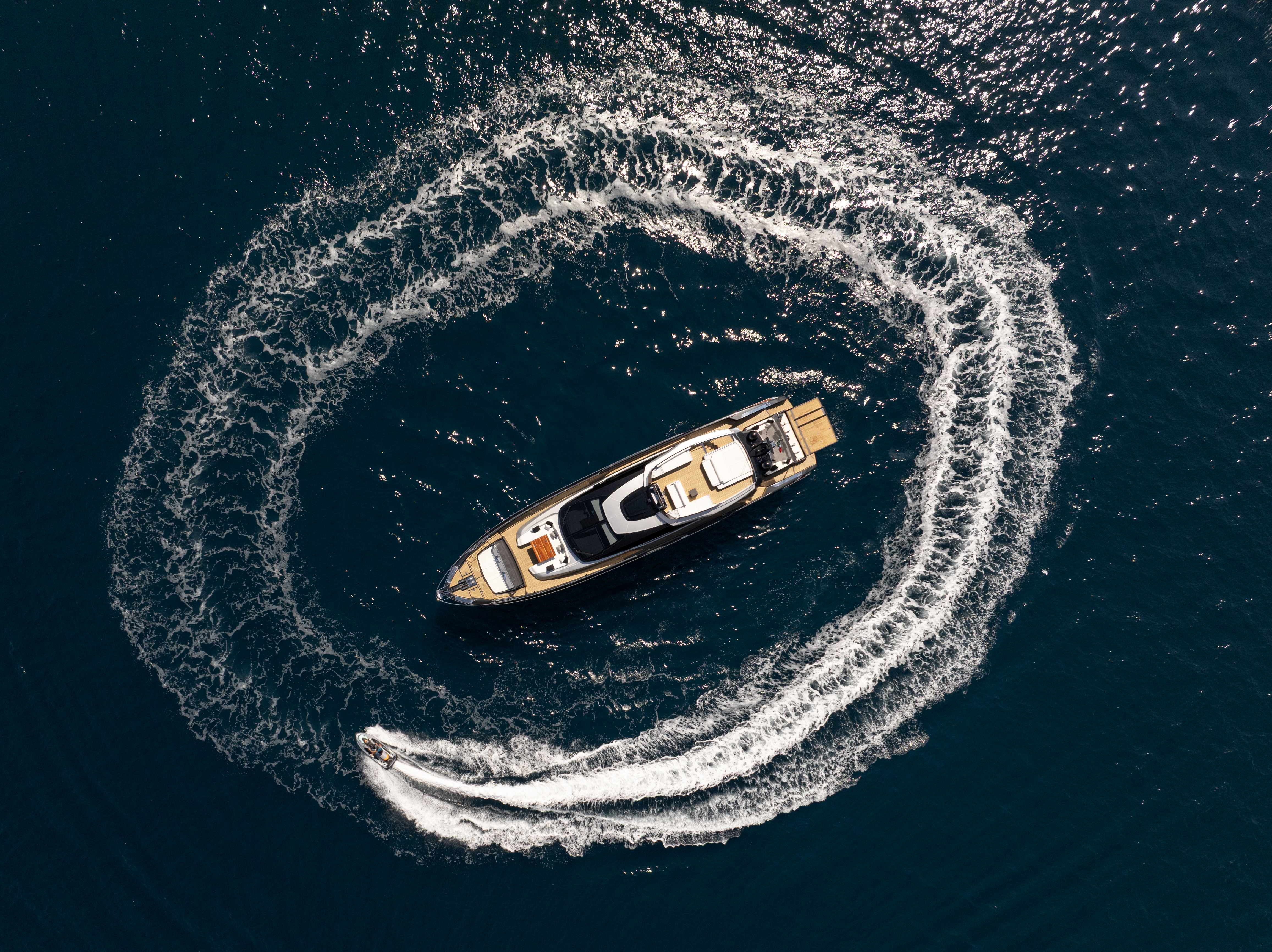 Luxury motor yacht tracing a spiral wake over deep blue Mediterranean waters — Sardinia yacht charter Costa Smeralda